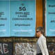A woman walks past posters debunking the 5G conspiracy theory causes covid-19